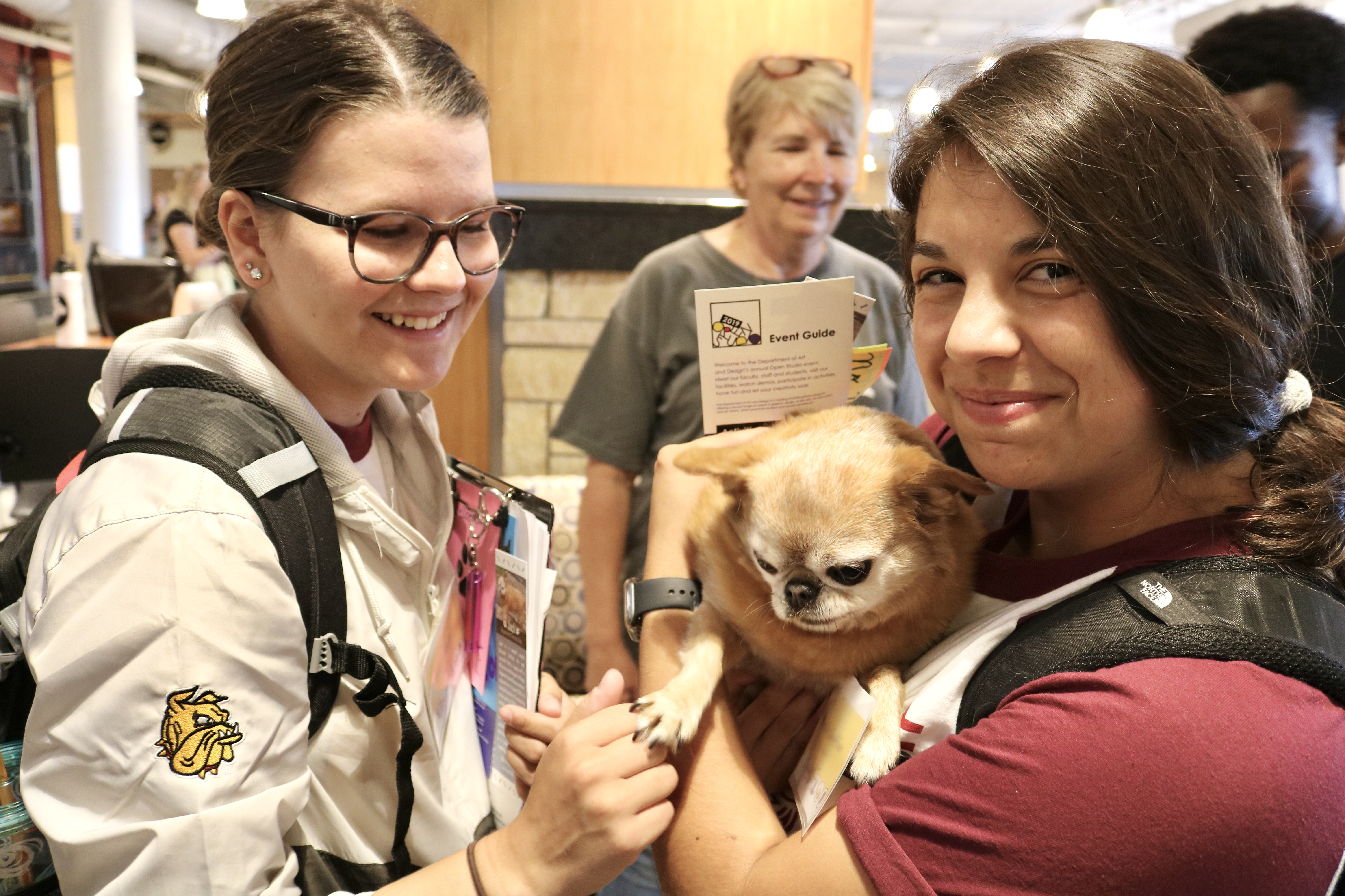 Two event student volunteers holding a cute dog!